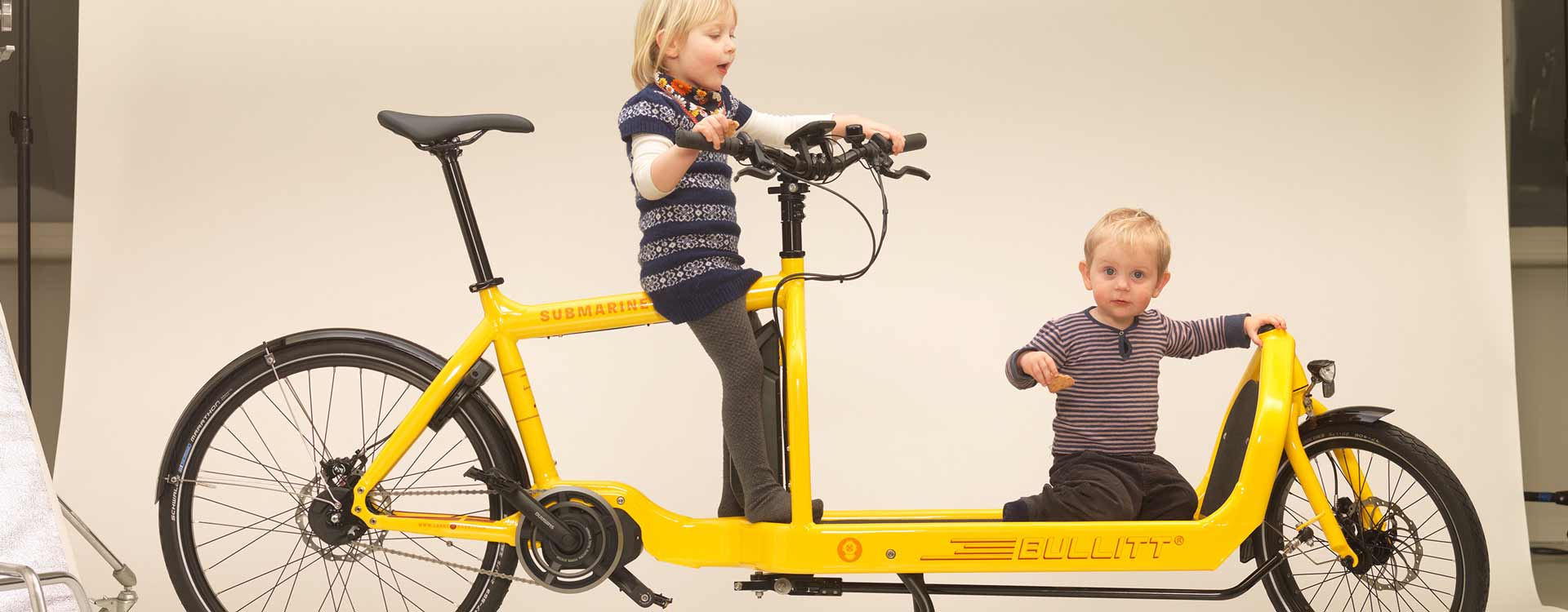 Kinder spielen auf einem gelben Bullitt Lastenrad