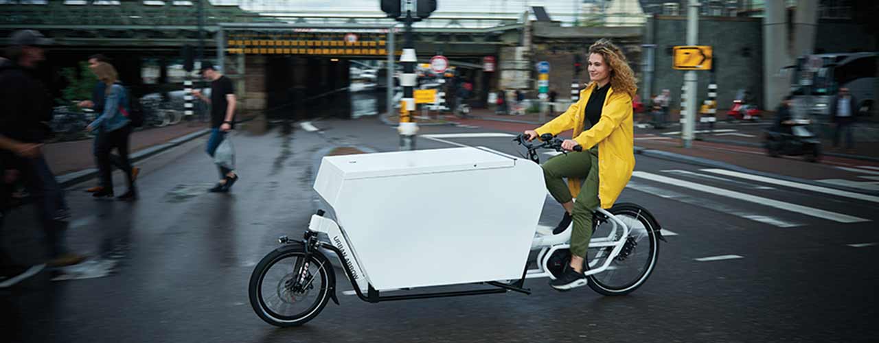 Eine Frau fährt Cargo-Lastenrad durch eine Straße