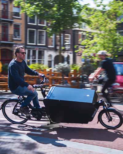 Mann fährt Urban Arrow Cargo Lastenrad durch die Stadt