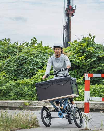 Frau fährt Dreirad Lastenfahrrad mit Neigungstechnik